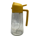 Clear glass bottle with yellow lid and handle on a textured gray background