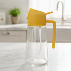Clear glass bottle with yellow lid and handle on a textured gray background